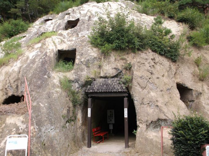 四角い穴がいくつも開いた岩山と、地下軍需工場跡の入口